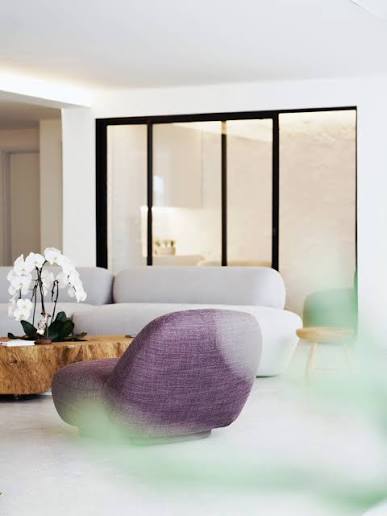 Sala de estar clara da Casa Amelis, com poltrona e orquídeas